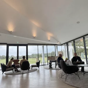 Membres échangeant dans un salon avec vue sur un parcours de golf lors d’une rencontre du Cercle Épicurien Wines & Tees
