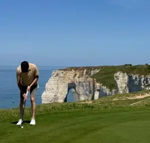 Golfeur sur le green du Golf d’Étretat face aux falaises normandes photographié par Wines and Tees.